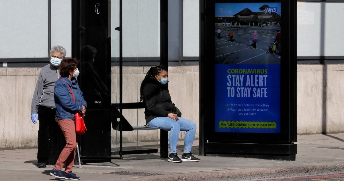 People wait at a bus stop in London on May 12, 2020.