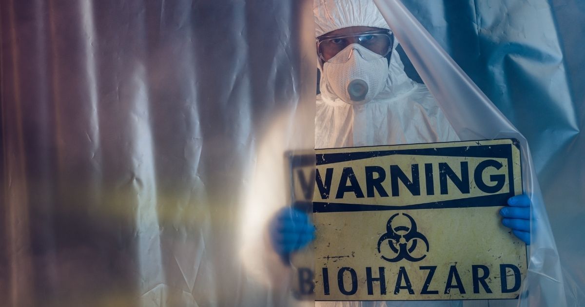 This stock photo portrays a man holding up a biohazard warning sign. One official is discussing the possibility that COVID-19 may have been part of a Chinese offensive bioweapons program.