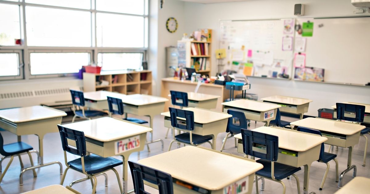 An empty classroom is pictured in the stock image above.