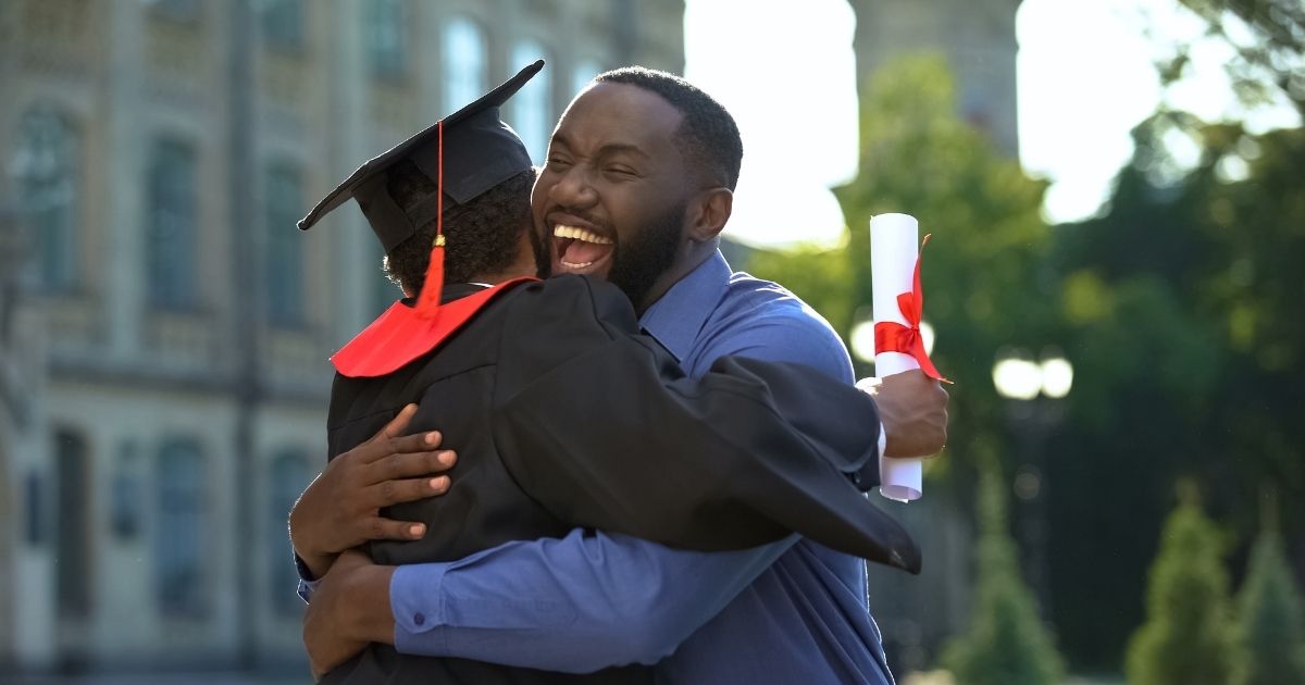A father is pictured hugging his son after he graduates from college in the stock image above.