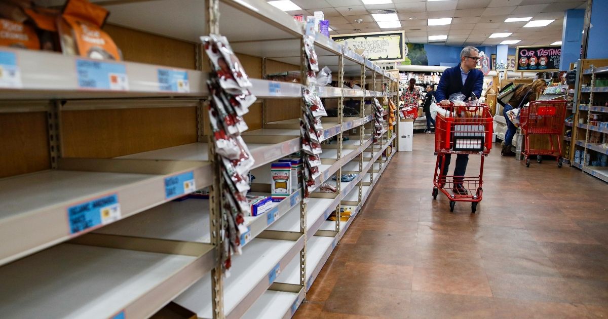 In this March 13, 2020, file photo, shoppers browse empty shelves at a supermarket in Larchmont, New York, amid panic-buying due to the coronavirus outbreak.