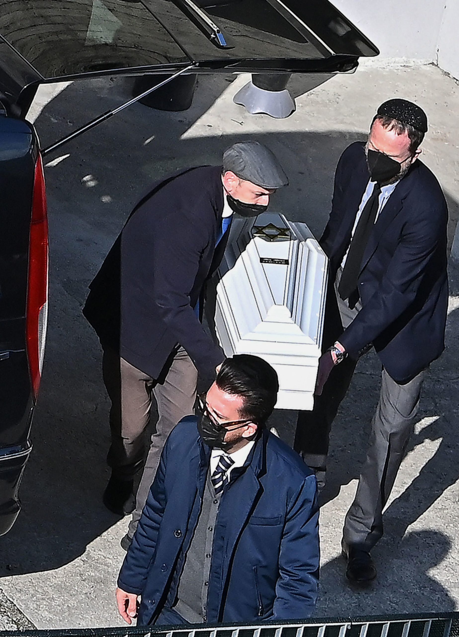 A photo obtained from Italian news agency Ansa and taken on May 26, 2021 outside the morgue of the Castelli hospital of Verbania-Pallanza on Lake Maggiore, shows people carrying the coffin of one of the Israeli victims of the cable car crash that occured in nearby Stresa on May 23.