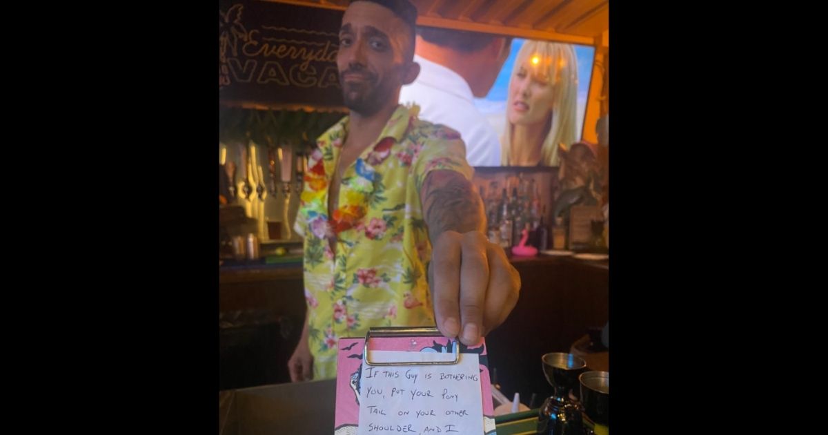 Bartender Max Gutierrez hands a disguised note to a patron being harassed by a male customer at a bar in St. Petersburg, Florida.