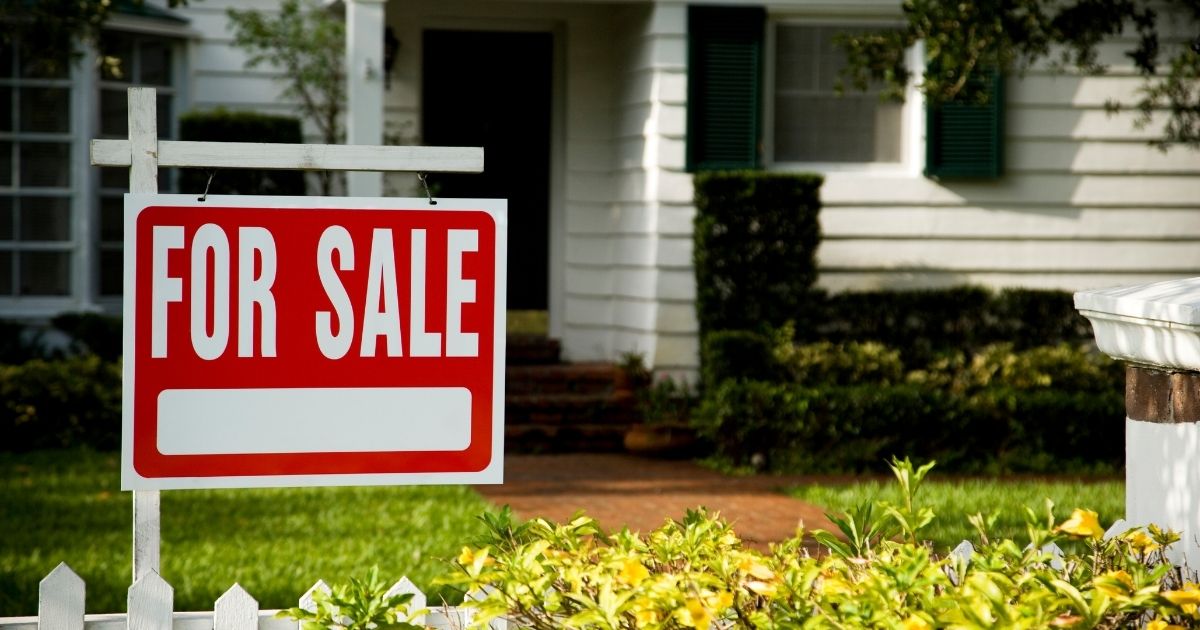 A "for sale" sign is pictured in front of a house.