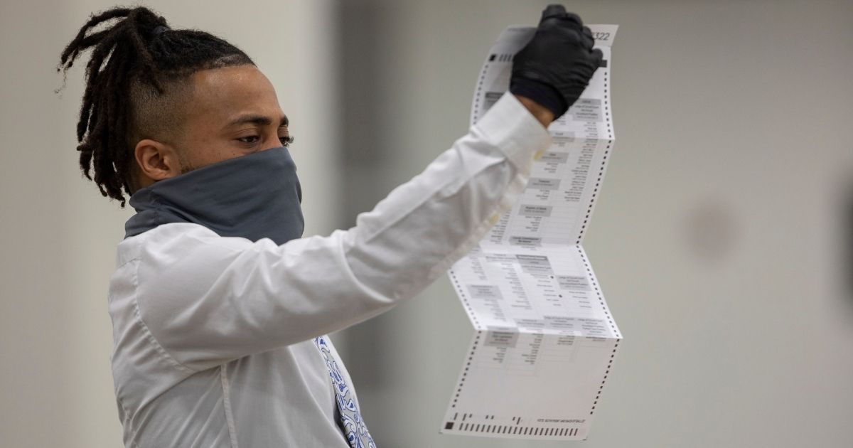 A worker with the Detroit Department of Elections inspects an absentee ballot at the Central Counting Board in the TCF Center on Nov. 4, 2020, in Detroit.