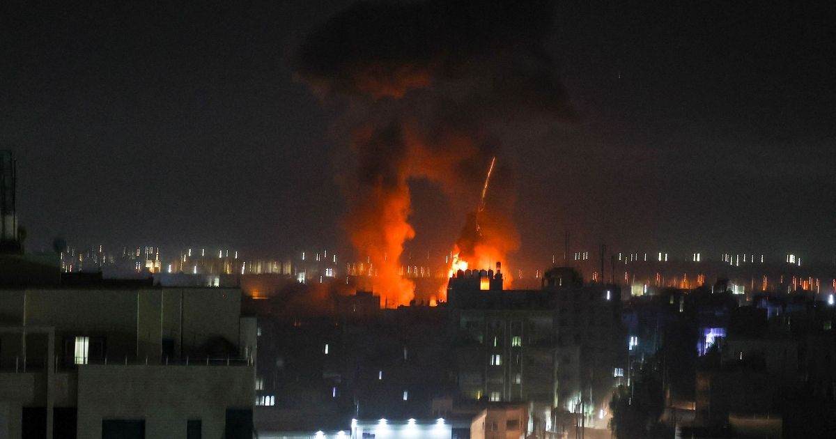 Explosions light up the night sky above buildings in Gaza City on Friday.