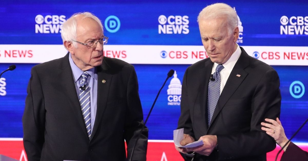 Then-presidential candidates independent Sen. Bernie Sanders of Vermont, left, and now-President Joe Biden interact at a break during the Democratic presidential primary debate at the Charleston Gaillard Center on Feb. 25, 2020, in Charleston, South Carolina.