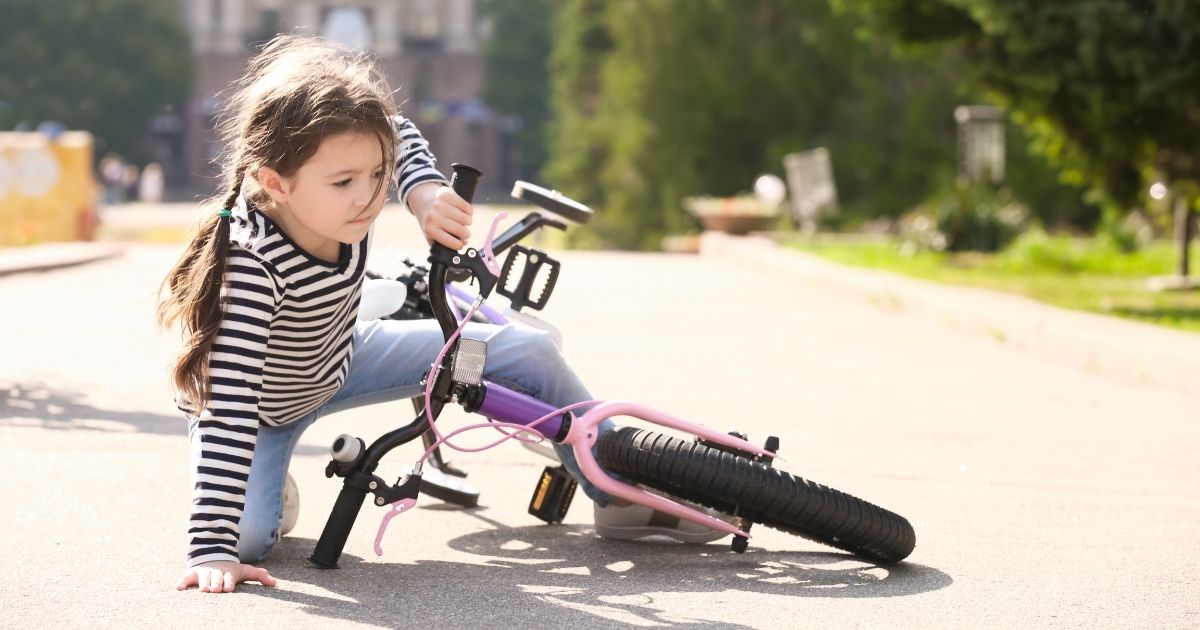A child is pictured after falling off her bike in the stock image above.