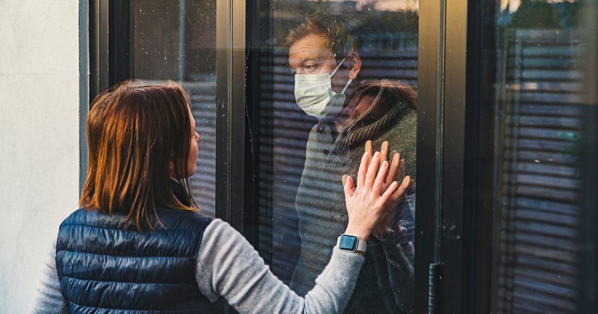 This stock photo portrays a woman looking in at a man wearing a mask in quarantine. A recent MedRxiv study found that mask mandates did not have a significant impact on lowering the spread of the coronavirus.