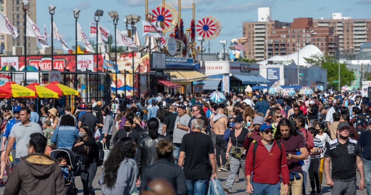 People with and without masks walk on a crowded boardwalk at Coney Island in the Brooklyn borough of New York on Memorial Day.