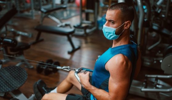 A man is pictured working out in a mask.
