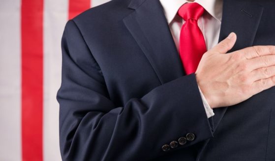 The above stock photo shows a man in front of the American flag, saying the pledge of allegiance.