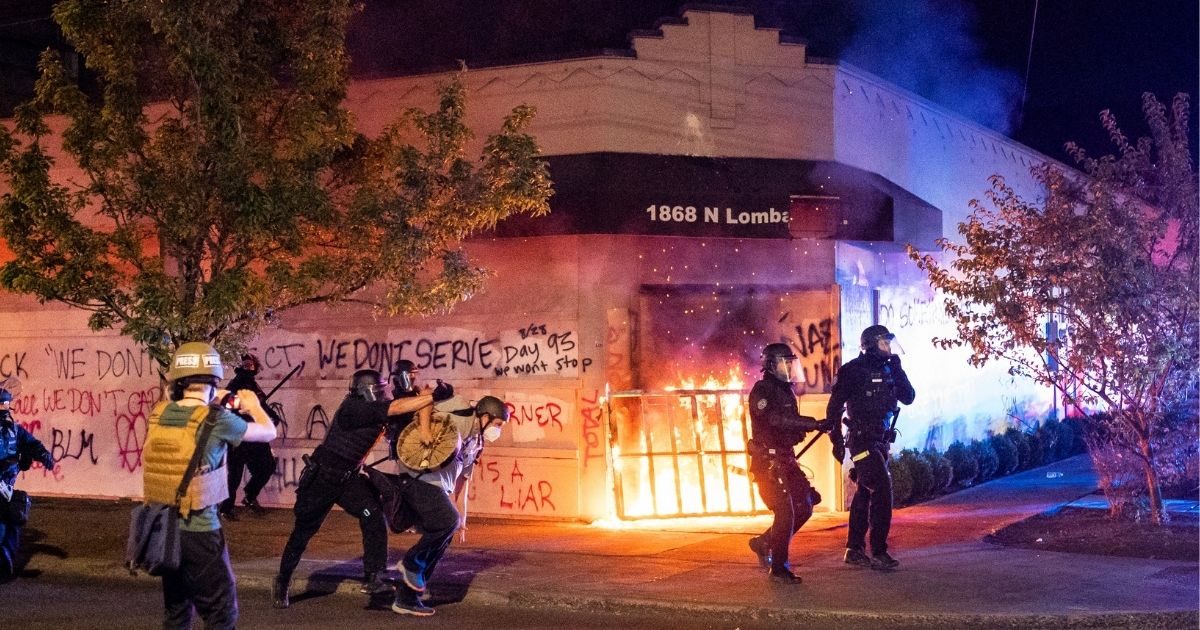 Police officers in Portland, Oregon, disperse a crowd after rioters set fire to the Portland Police Association building early in the morning of Aug. 29, 2020.