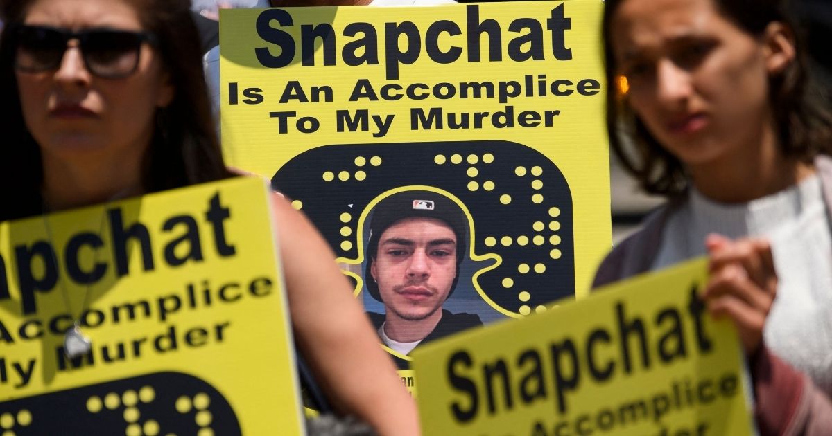 Family and friends of people who died after being poisoned by pills containing fentanyl carry signs as they protest near the Snap, Inc. headquarters, makers of the Snapchat social media application, on June 4 in Santa Monica, California.