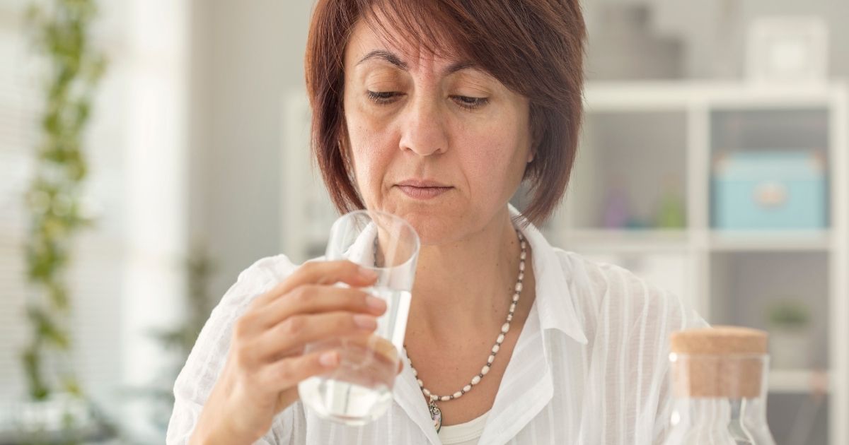 The above stock photo shows a woman looking at her water glass.