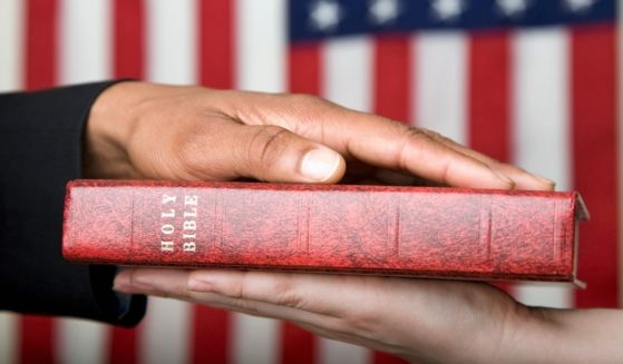 This stock image portrays a person swearing on the Bible in front of an American flag. HarperCollins Christian Publishing, Zondervan's parent company, retracted an agreement to print a "God Bless the USA" Bible edition.