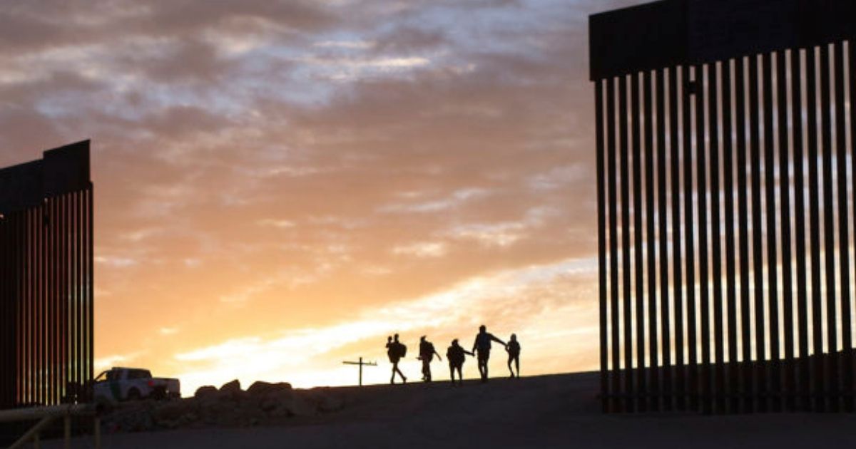 A pair of migrant families from Brazil passes through a gap in the border wall to reach the United States after crossing from Mexico in Yuma, Arizona, on Thursday.