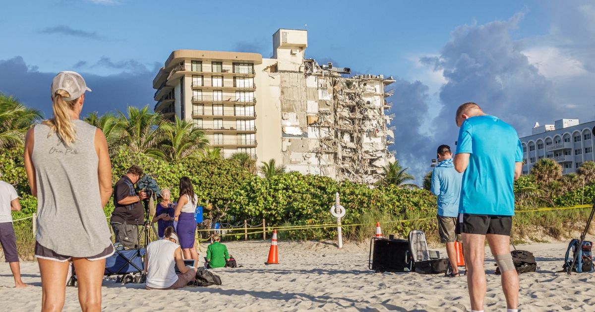 Reporters and bystanders view the wreckage of the collapsed Champlain Towers South in Surfside, Florida.