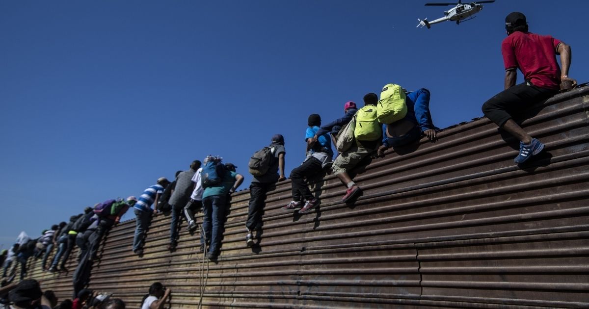 A group of Central American migrants -- mostly Hondurans -- climb a metal barrier on the Mexico-U.S. border near El Chaparral border crossing, in Tijuana, Baja California State, Mexico, on Nov. 25, 2018.