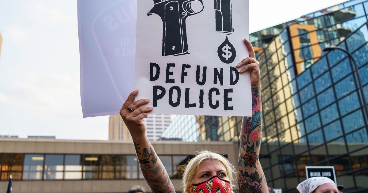 A protester holds a sign reading "Defund the Police" outside Hennepin County Government Plaza during a demonstration against police brutality and racism on Aug. 24, 2020, in Minneapolis, Minnesota.