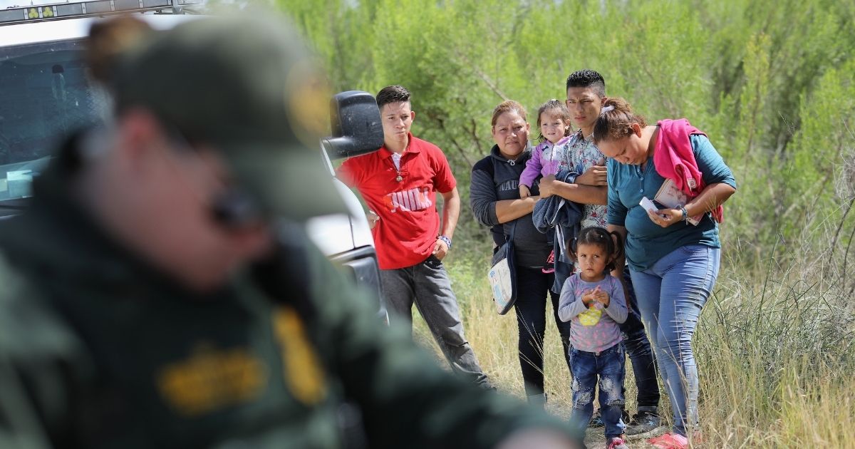 Central American asylum seekers wait as U.S. Border Patrol agents take groups of them into custody on June 12, 2018, near McAllen, Texas.