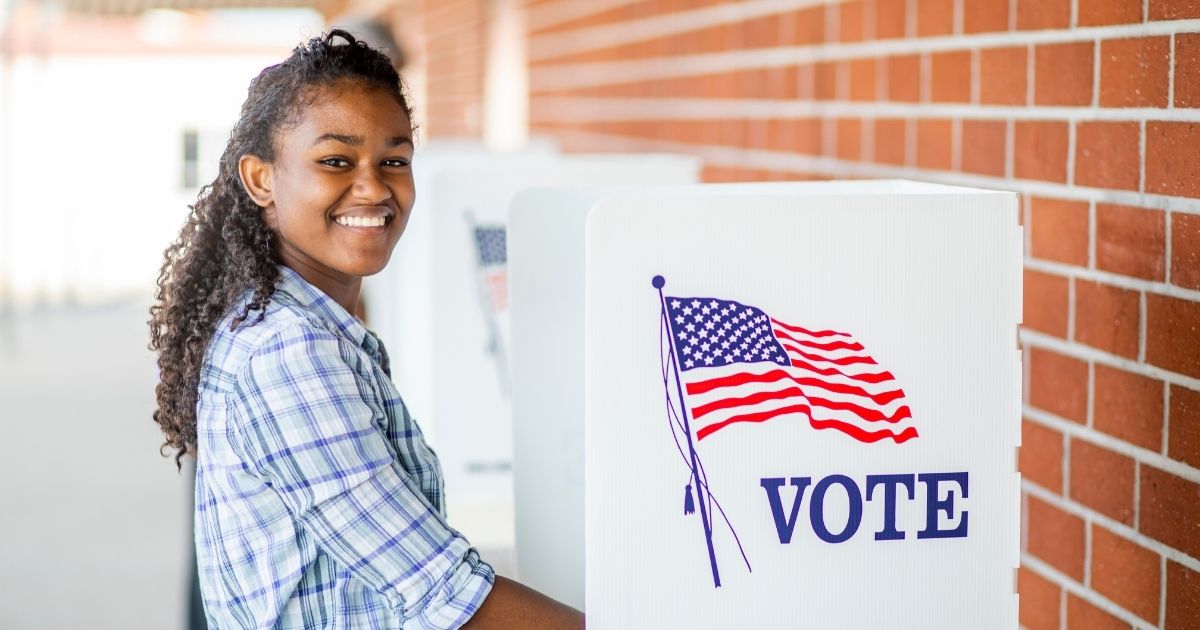 The above stock image shows a woman voting.