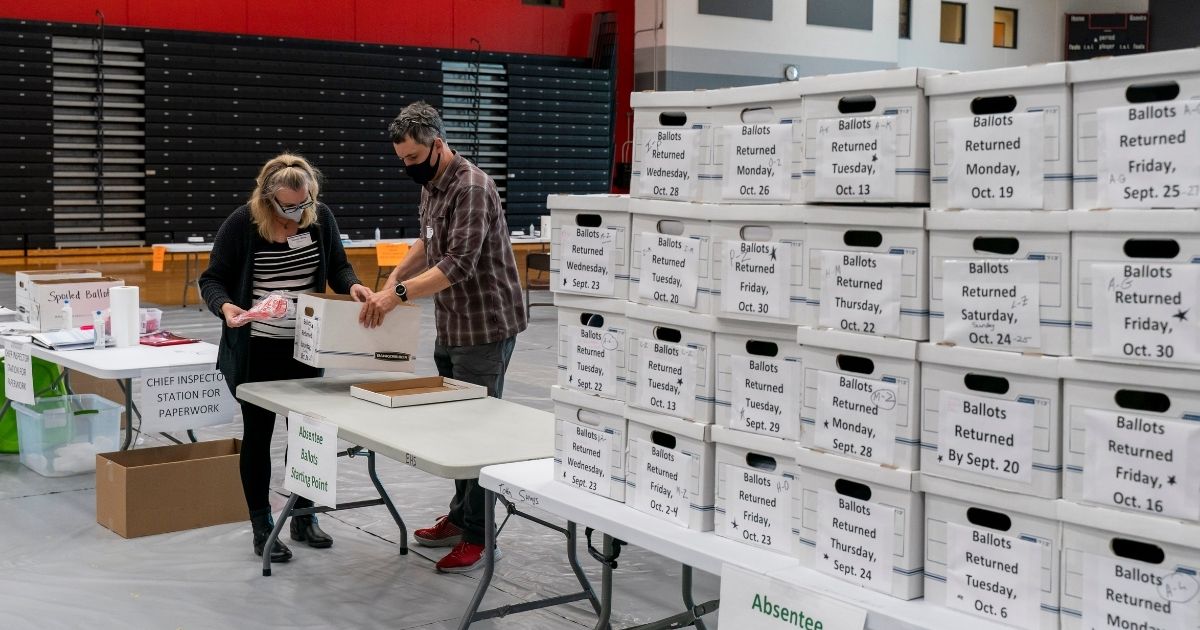 Poll workers check a box of absentee ballots at Sun Prairie High School on Nov. 3, 2020, in Sun Prairie, Wisconsin.