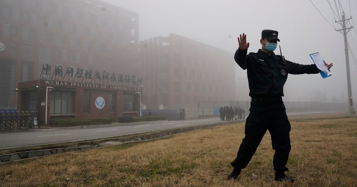 A security official moves reporters away from the Wuhan Institute of Virology in China's Hubei province after a World Health Organization team arrived for a field visit on Feb. 3, 2021.