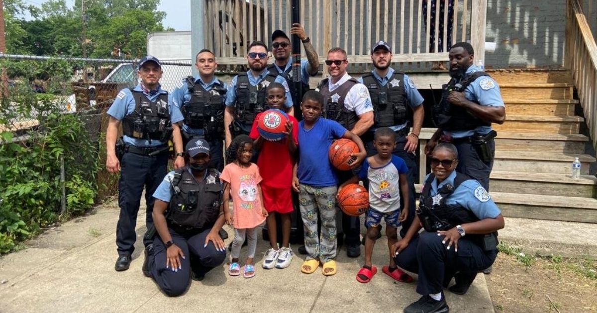 A group of Chicago police officers pose with the kids they bought a basketball hoop for.