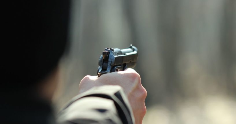 A man uses a gun in the above stock image.