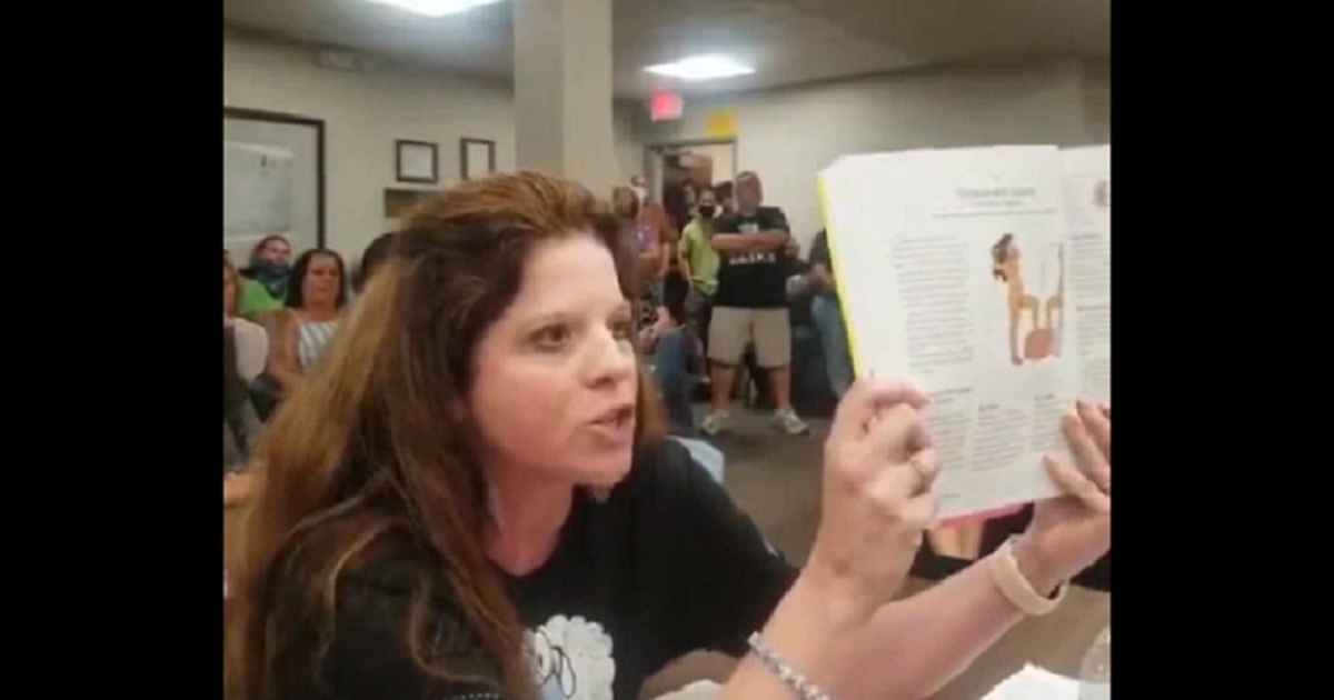 Becky Swan, a parent in Bloomington, Illinois, holds a sex education book during a school board meeting last week.