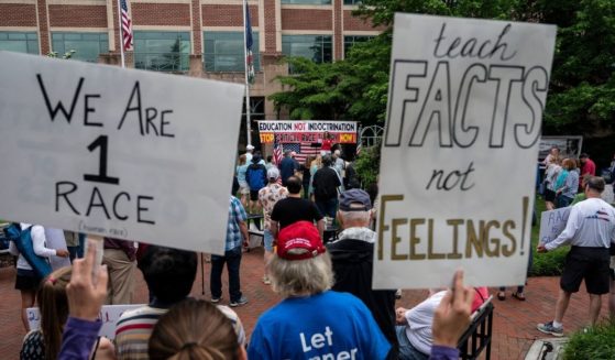 People hold up signs during a rally against critical race theory being taught in schools at the Loudoun County Government Center in Leesburg, Virginia, on June 12, 2021.