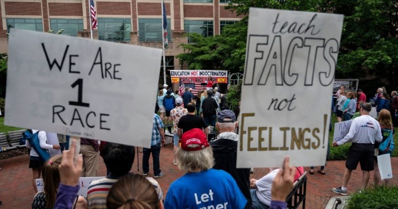 People hold up signs during a rally against critical race theory being taught in schools at the Loudoun County Government Center in Leesburg, Virginia, on June 12, 2021.