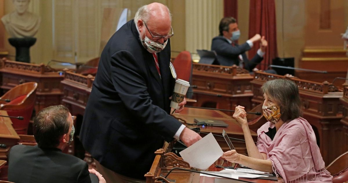Democratic state Sens. Mike McGuire, of Healdsburg, left, Jim Beal, of San Jose, center, and Nancy Skinner, of Oakland, members of the Senate Budget and Fiscal Review Committee, huddle after a hearing on the state budget in Sacramento, California, on June 12, 2021.