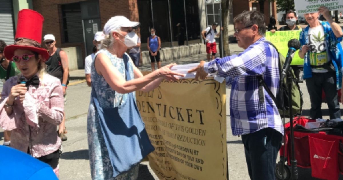 Vancouver City Council member Jean Swanson hands a "safe" drug sample to a man during an event on Wednesday.
