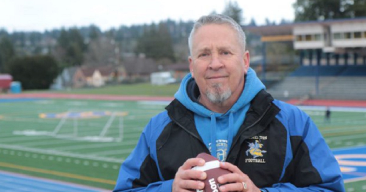 Former high school football coach Joe Kennedy, with a football in his hand a football field in the background.
