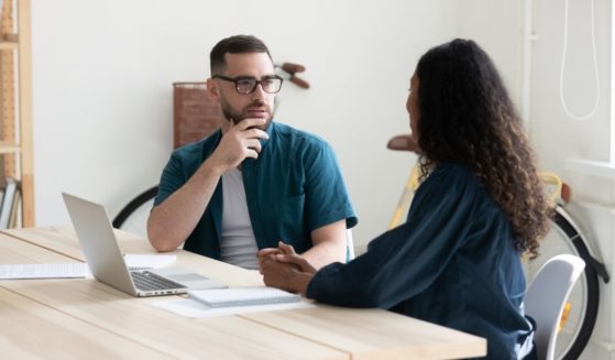 Two people are pictured having a conversation in the stock image above.