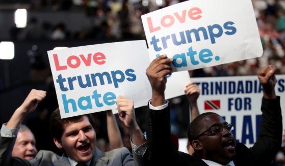 Delegates hold up signs that read "love trumps hate" during the opening of the first day of the Democratic National Convention at the Wells Fargo Center on July 25, 2016, in Philadelphia.