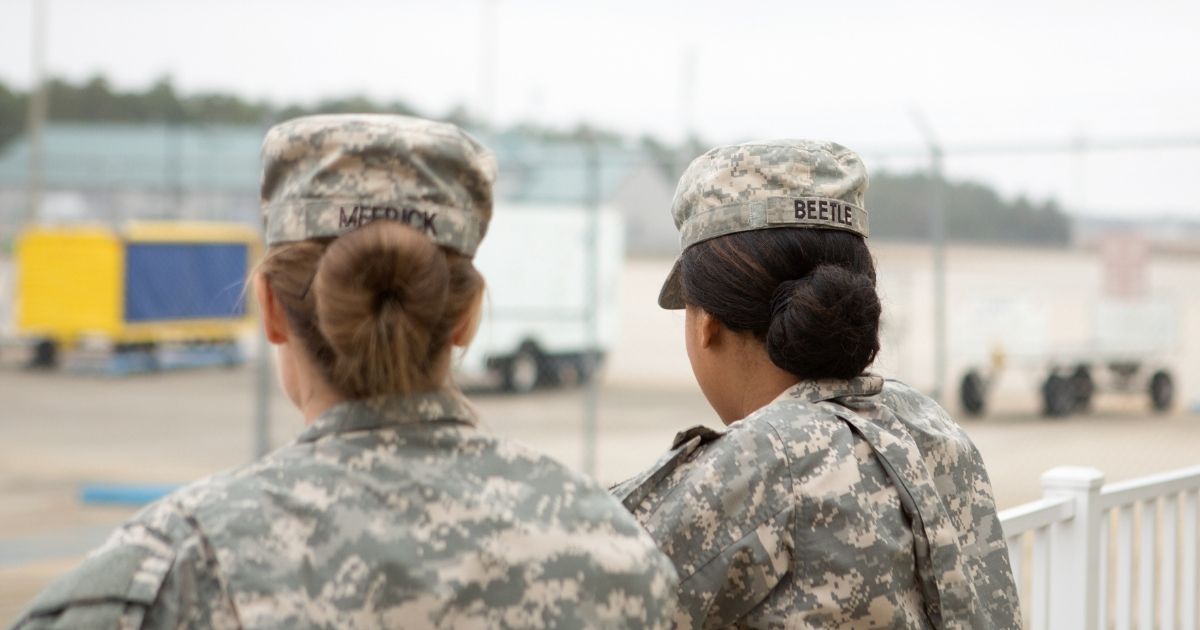 Two female soldiers look out over an airport