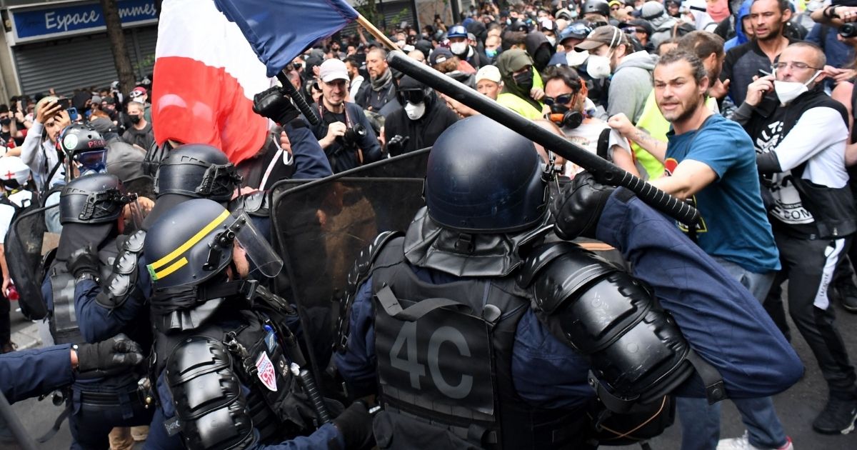 Protesters stand in front of riot police during a demonstration against French legislation making a COVID-19 health pass compulsory to visit a cafe, board a plane or travel on an inter-city train in Paris on Saturday.