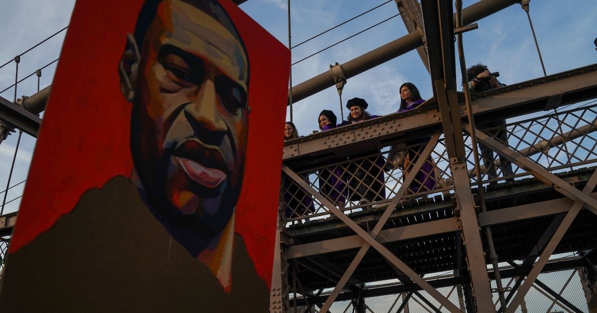 Spectators watch marchers cross the Brooklyn Bridge demanding police reform after a commemoration to honor the anniversary of George Floyd's death on May 25, 2021, in New York City.