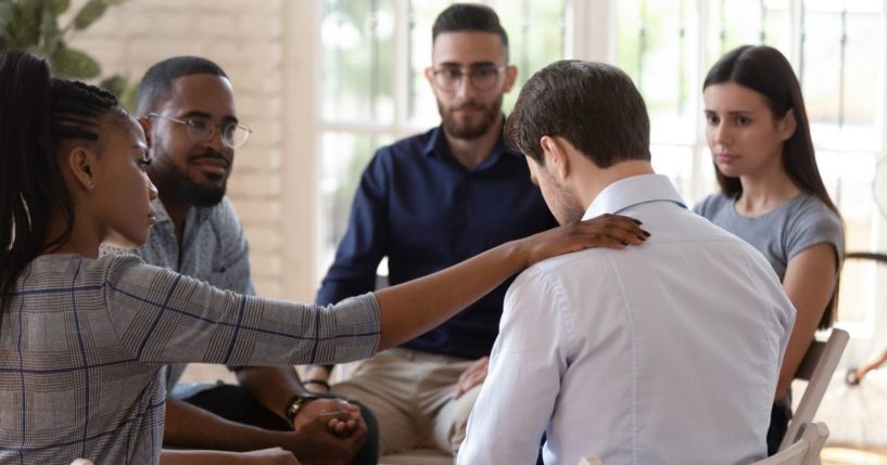 A group of people are seen comforting their friend in the stock image above.