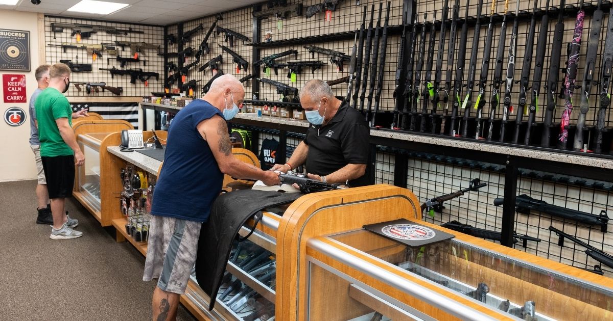 A gun shop employee shows guns to customers at SP Firearms Unlimited on Aug. 6, 2020 in Franklin Square, New York.