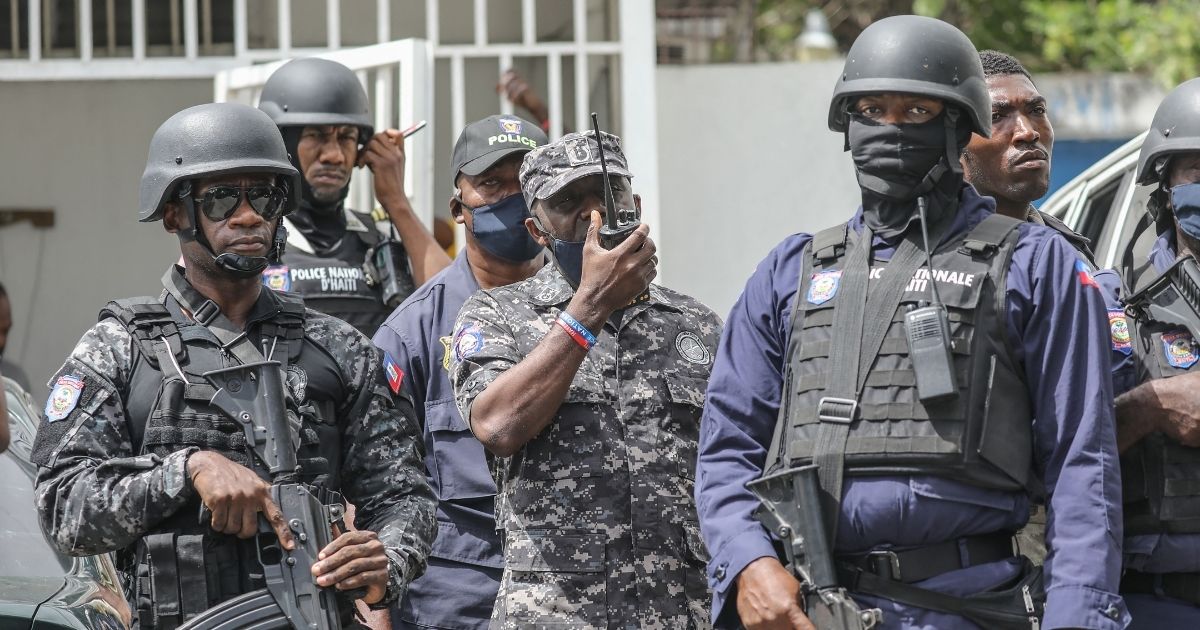 Leon Charles, head of the Police Nationale of Haiti, center, gives orders on a walkie-talkie as the crowd surrounds the Petionville Police station where armed men were accused of being involved in the assassination of President Jovenel Moïse in Port-au-Prince on Thursday.