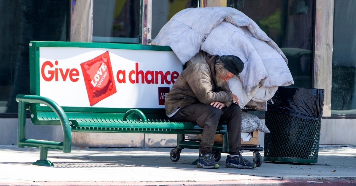 A homeless man sits on a bench on La Brea Ave on National May Day amid the COVID-19 pandemic on May 1, 2020, in Los Angeles.