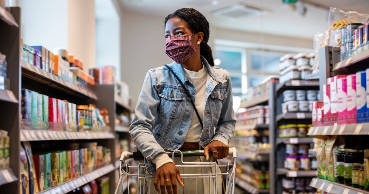The above stock photo shows a customer at a grocery store with a face mask on.