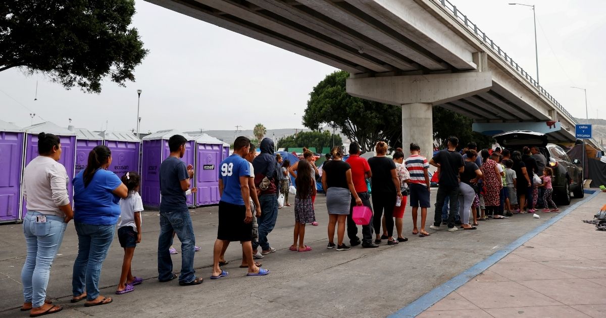 Asylum-seeking migrants wait in line for donated food at a makeshift migrant camp on the Mexican side of the San Ysidro Port of Entry on Thursday in Tijuana, Mexico.