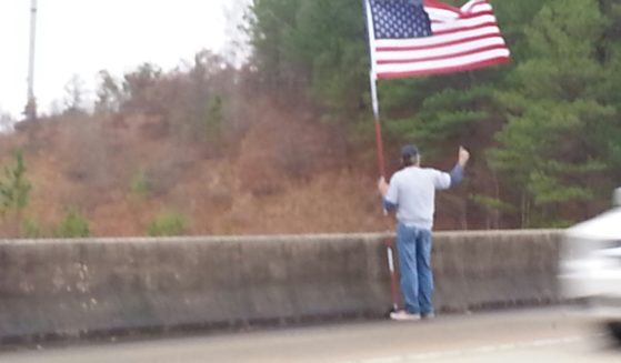 A man calling himself "Pappy" waves an American flag on an Alabama overpass on July 4, 2017.