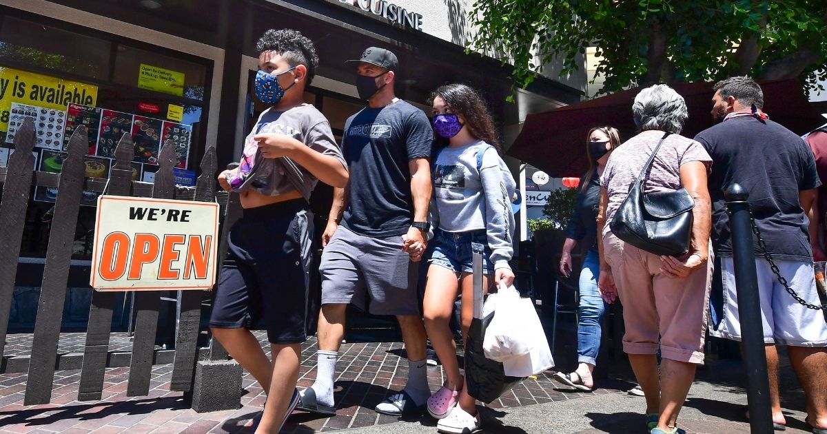 Face masks continue to be worn as people walk past restaurants open for business in Los Angeles on June 14, 2021.