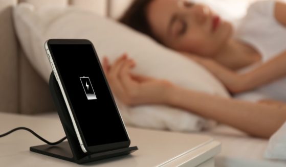 A person is pictured sleeping while her phone sits on a table next to her in the stock image above.